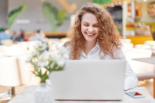 vrouw-achter-laptop Lachende vrouw achter een laptop.